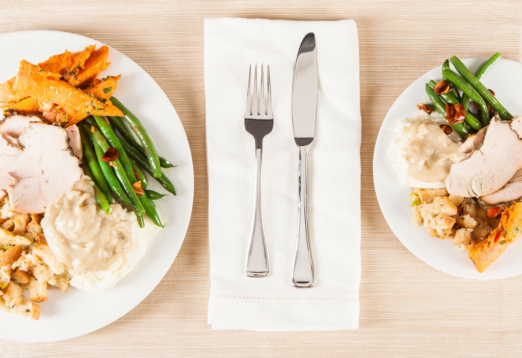 two plates of holiday food with napkin and utensils